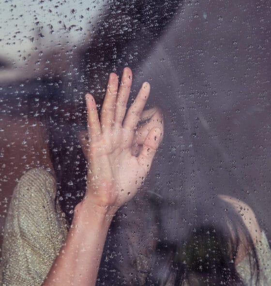 Photo of a woman crying at rainy window